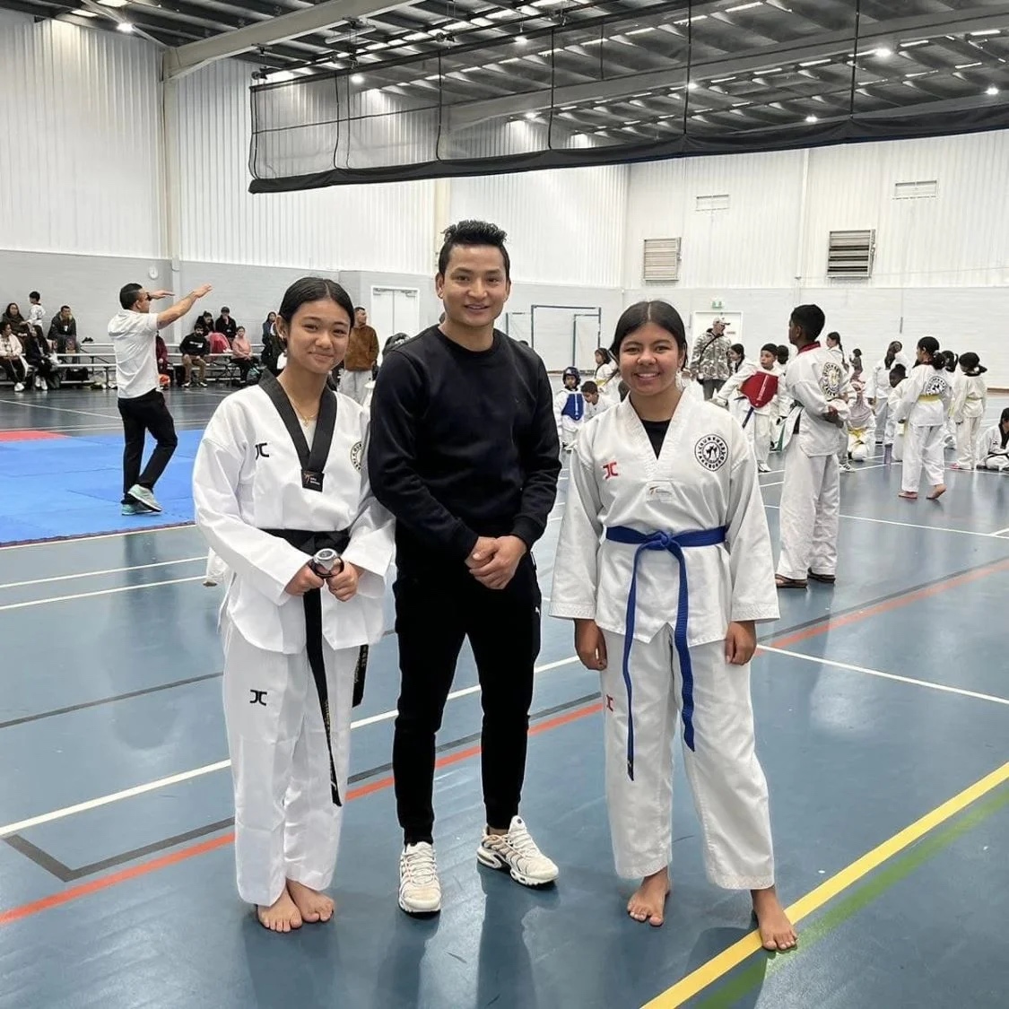 Young taekwondo students training together in a large hall