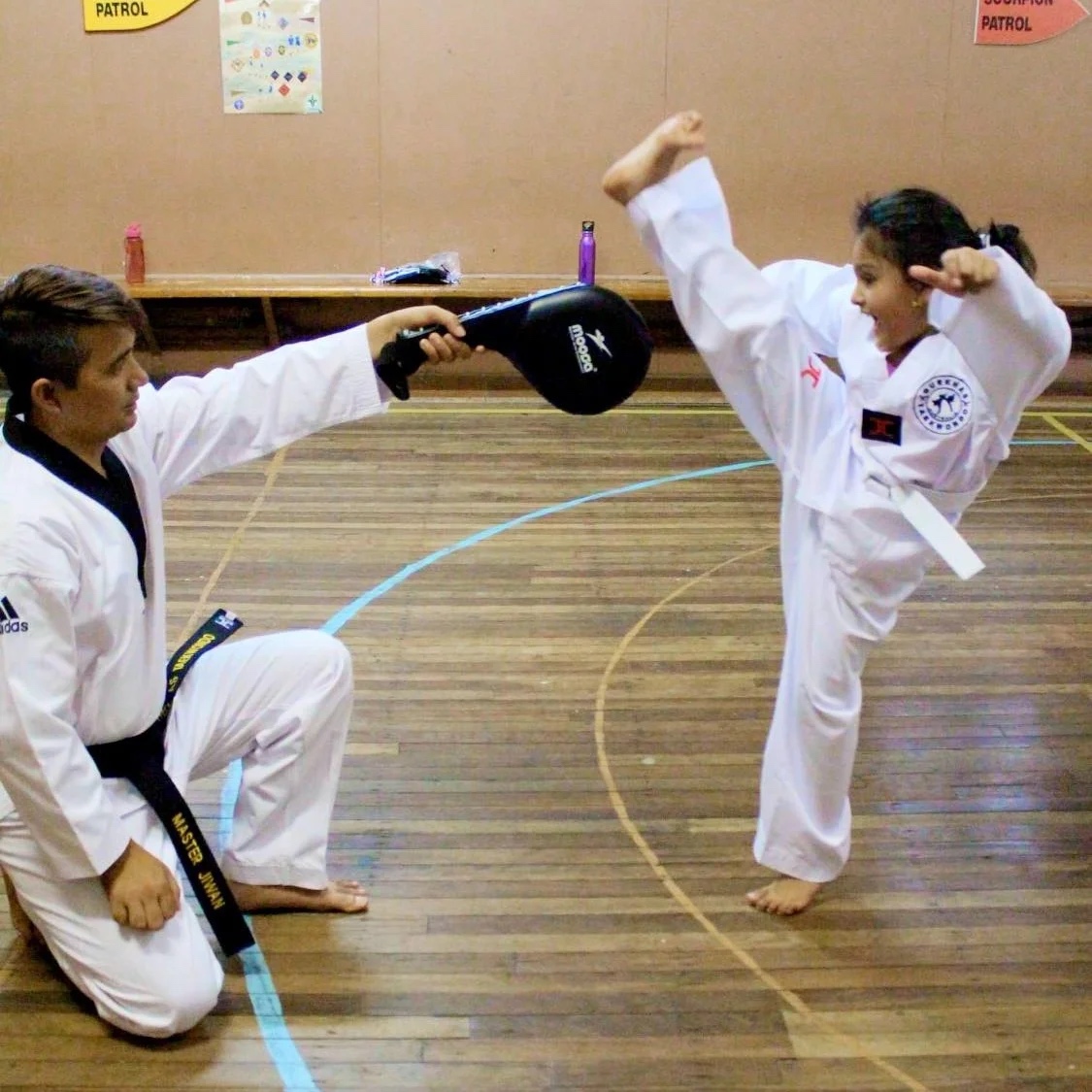 A young taekwondo student practicing a kick with an instructor